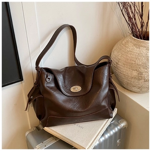 Detail of dark brown leather tote featuring an oval silver twist-lock and practical side pockets