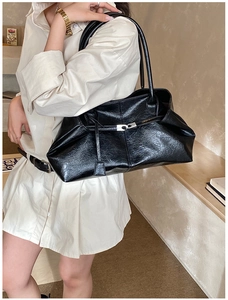 Detail of black glossy crinkled leather texture on tote bag with silver buckle and thin straps