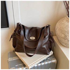 Close-up of vintage brown leather tote bag with metallic oval twist lock detail