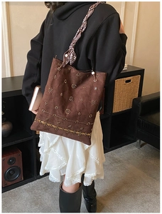 Detail of suede tote bag with heavy beadwork, rivets and floral scarf accent