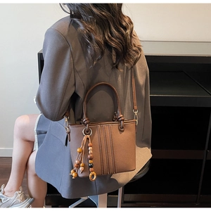 Détail du sac seau marron vintage avec coutures blanches et pompon en perles de bois