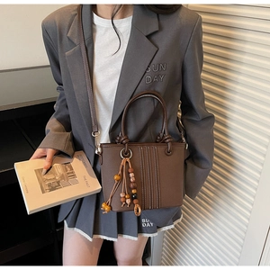 Détail du sac seau vintage marron avec breloque en perles de bois et surpiqûres