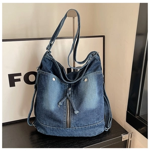 Detail einer dunkelblauen Hobo-Tasche aus gewaschenem Denim mit Nieten und Reißverschluss