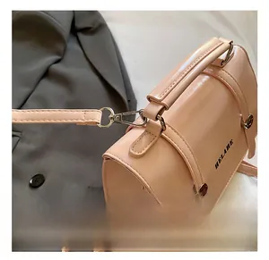 Detailed close-up of pink glossy leather handbag showing metal hooks and detachable strap
