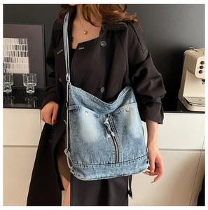 Detail der hellblauen Denim-Tasche mit Reißverschluss und Metallschnalle am Modell