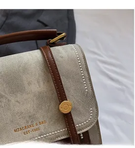 Detail van vintage canvas crossbodytas met lederen biezen en gouden metalen sluiting