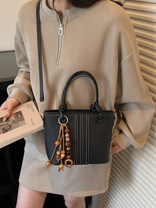 Sac seau noir avec coutures contrastées et breloque en perles de bois porté par un mannequin