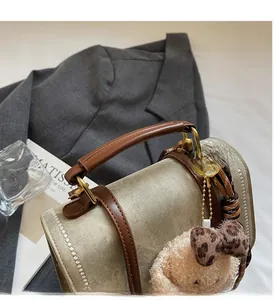 Detail van canvas mini handtas met lederen handvat en schattige teddybeer hanger