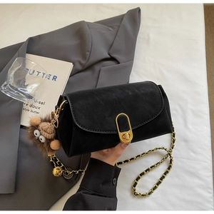 Détail du sac carré noir avec fermoir doré et accessoire de charme en peluche marron