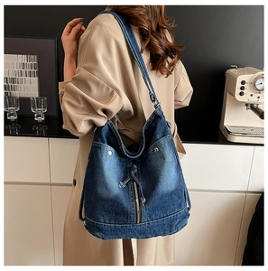 Detail der blauen gewaschenen Denim-Tasche mit Metallnieten und Reißverschluss am Riemen