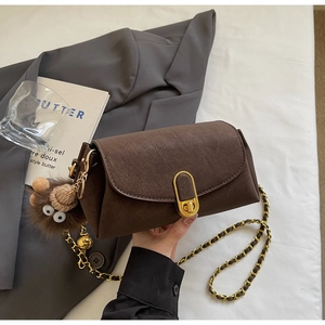 Détail d'un sac oreiller marron vintage avec fermoir doré et charme peluche