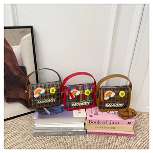 Drei Retro-Karotaschen mit Gänseblümchen-Stickerei auf einem Bücherstapel-Display