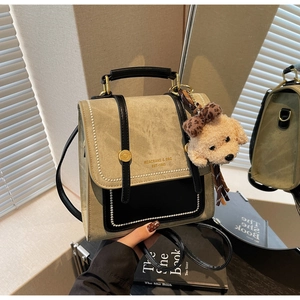 Detail van vintage crossbodytas met metalen studs en schattige beer pluche hanger