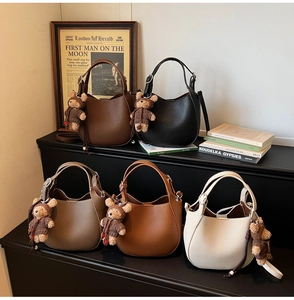 Detail view of five textured faux leather bucket bags with cute bear charms in warm brown tones
