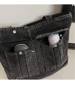 Close-up of deep gray washed denim tote bag showing functional multi-pocket storage