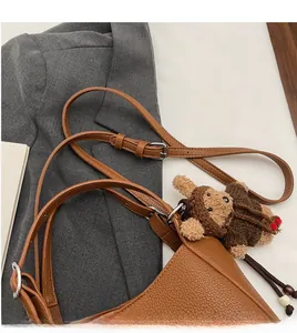 Detail of brown lychee pattern leather handbag with adjustable strap and cute bear charm