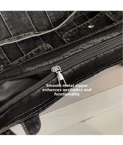 Close-up of smooth silver zipper puller and white stitching on black denim tote bag
