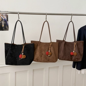 Présentation de grands sacs cabas vintage en daim noir et marron sur des cintres