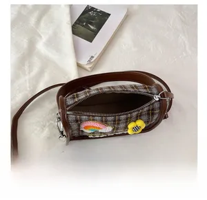 Makroansicht der karierten Zylindertasche mit Innenraum und Blumenstickerei