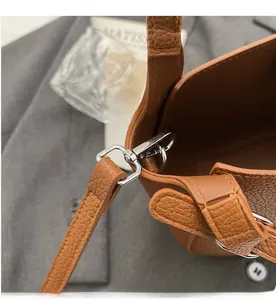 Detailed shot of silver metal hook and leather texture on a brown bucket bag
