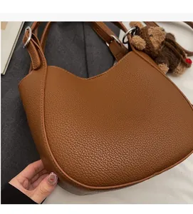 Detail of dark brown pebbled leather handbag with silver rings and bear charm