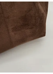 Detail of dark brown suede tote bag featuring premium matte texture and double stitching