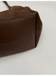 Detail view of the wide rectangular base and stitching on dark brown suede tote bag