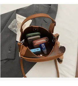 Brown lychee leather bucket bag showing spacious interior with phone and wallet