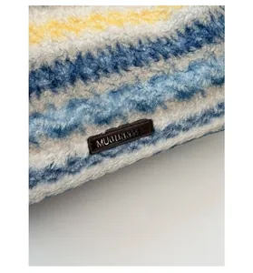 Detail showing plush fabric texture and striped pattern with a sewn leather logo tag