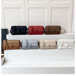 Variety of minimalist crossbody bags in seven colors displayed on white stairs