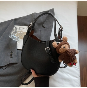 Close-up of black lychee grain leather bucket bag with silver buckle and teddy bear charm