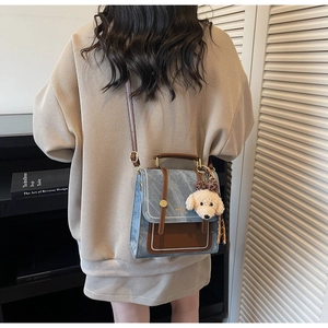 Detail van vintage blauwe crossbodytas met lederen handvat en schattige pluche hond hanger
