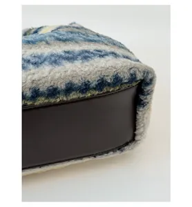 Close-up of plush striped tote bag with reinforced dark brown faux leather base