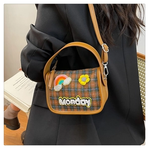 Modell mit Vintage-Karotasche mit Monday-Stickerei auf einem schwarzen Blazer