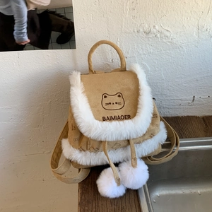Detailed view of khaki bucket backpack with cat embroidery and plush pom-poms