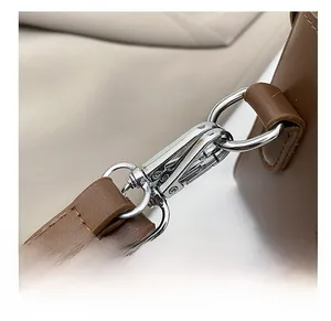 Detail of silver alloy hook and fine stitching on brown synthetic leather strap