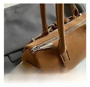 Detail of silver zipper and hardware on brown frosted cylinder handbag with soft texture