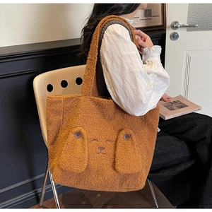 Detailed view of brown plush tote bag featuring cute cartoon dog face embroidery and ears