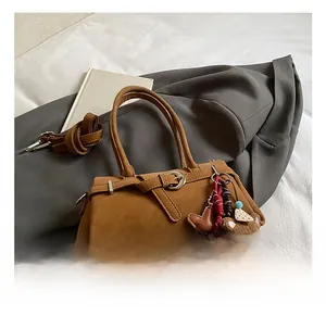 Close-up of retro brown leather baguette bag with charms on dark grey blazer