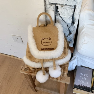 Detail of a brown suede bucket backpack with cat embroidery and white plush pom-poms