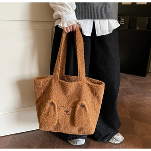 Close-up of brown plush tote bag with embroidered cartoon dog face and 3D ears detail