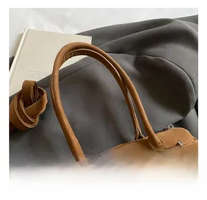 Close-up of the comfortable leather handle and vintage metal buckle on a brown handbag