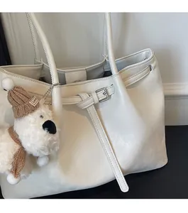 Gros plan sur un cabas crème en cuir texturé avec boucle argentée et breloque chien