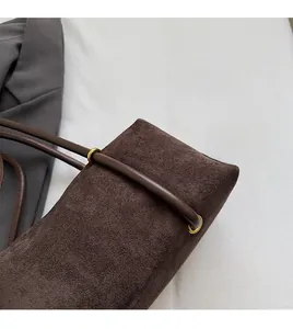 Close-up of vintage dark brown suede texture and metal ring buckle on the shoulder bag