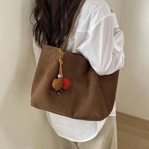 Vue détaillée du grand sac cabas en daim marron foncé avec pompons et breloques perlées