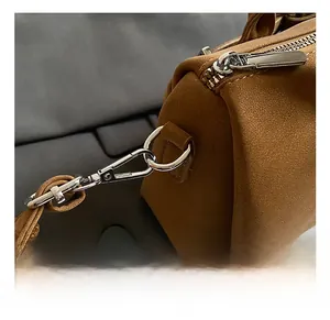 Close-up of premium silver metal hooks and zipper on a brown leather shoulder bag
