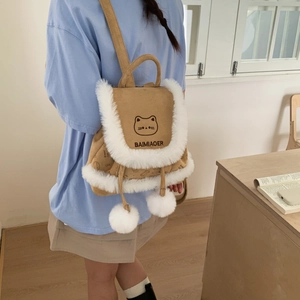 Detail of khaki bucket backpack with faux fur trim, plush pom-poms, and cat embroidery