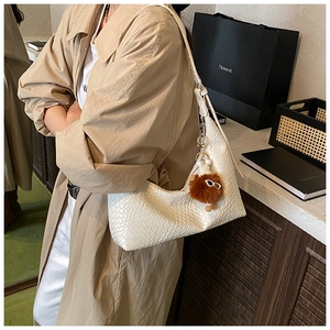 Detail of cream woven texture shoulder bag with cute bear charm and curved zip design