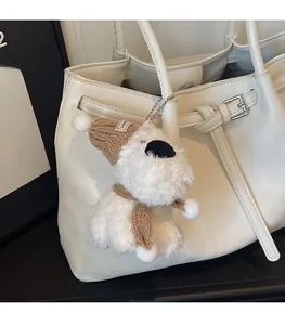 Détail d'un charme chiot en peluche blanche avec bonnet sur un sac cabas blanc