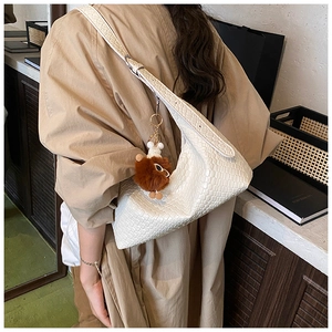 Detail of white crocodile texture hobo bag with a cute brown plush bear charm